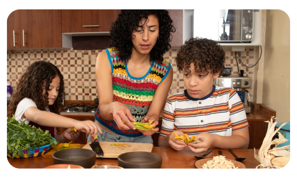 Adult cooking dinner with two children